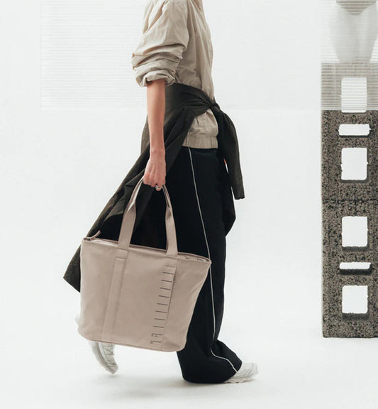 容量20リットルのトートバッグ、Db Essential Tote 20L の商品着用画像。旅好きやスポーツ好きの大人に向けた、シンプルでスポーティなデザインです。色はFogbow Beige
