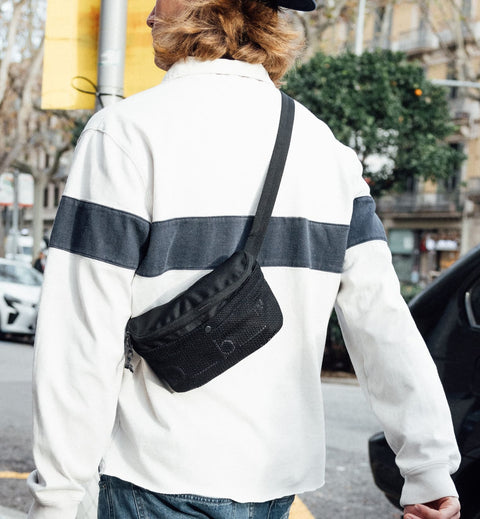 旅行やスポーツに最適なDbのボディバッグ、Hauler Sling Bag 3L。アクティブに動ける3L容量のスリングバッグ着用シーン。色はBlack Out
