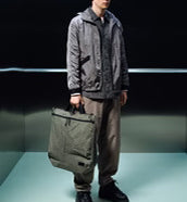  Db(ディービー)の大容量トートバッグ「Utility Tote 32L」。旅行やスポーツ、アクティブな日常に最適なシンプルで機能的なバッグのモデル着用シーンです。